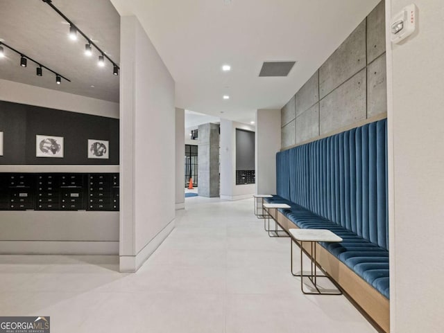 hall featuring track lighting, mail boxes, and light tile patterned flooring