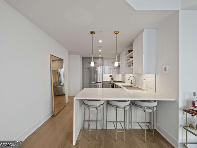 kitchen with decorative light fixtures, white cabinets, decorative backsplash, kitchen peninsula, and high end fridge