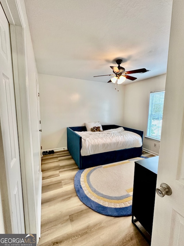 bedroom with ceiling fan, hardwood / wood-style floors, and a textured ceiling