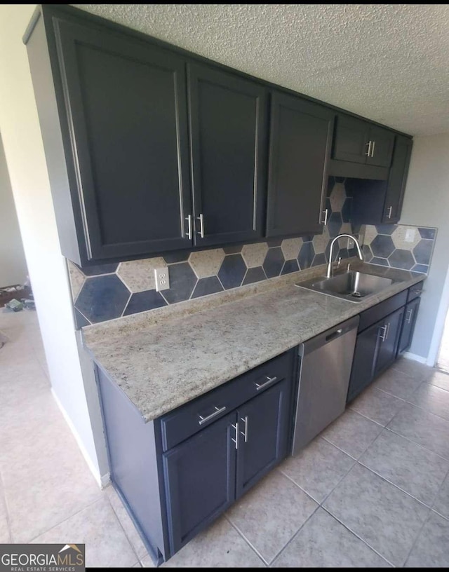 kitchen with sink, backsplash, stainless steel dishwasher, light tile patterned floors, and a textured ceiling