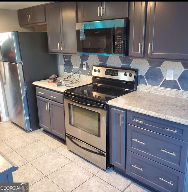 kitchen featuring stainless steel appliances, light tile patterned floors, and backsplash