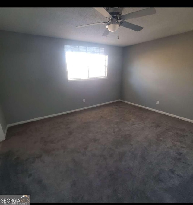 empty room with ceiling fan and dark carpet