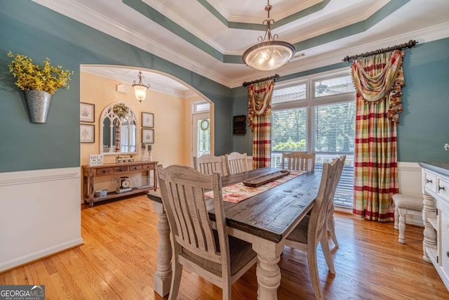 dining space featuring ornamental molding, light hardwood / wood-style floors, and a tray ceiling