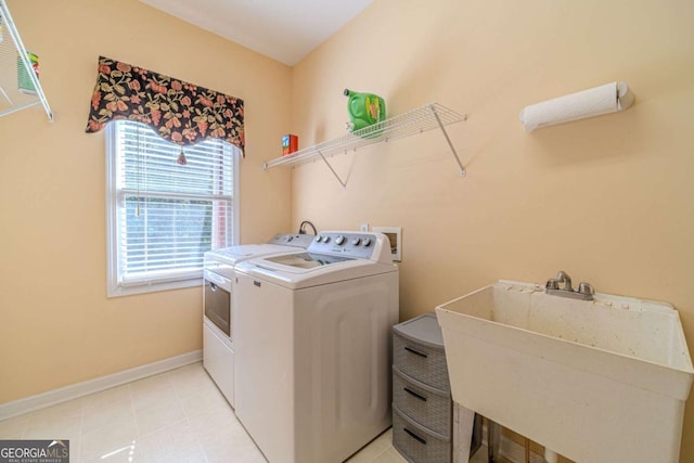 laundry room featuring light tile patterned flooring, washer and clothes dryer, and sink