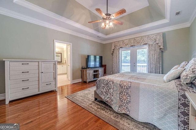 bedroom featuring french doors, hardwood / wood-style floors, access to exterior, and a tray ceiling