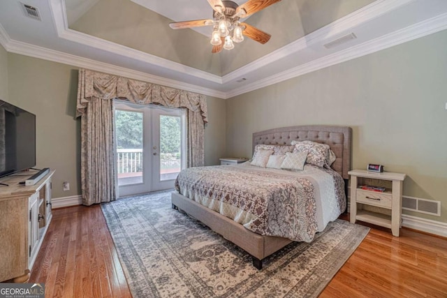 bedroom featuring french doors, access to outside, ornamental molding, a raised ceiling, and light hardwood / wood-style floors