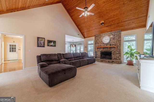 carpeted living room featuring ceiling fan with notable chandelier, a stone fireplace, high vaulted ceiling, and wood ceiling