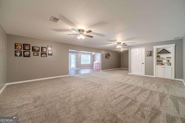 unfurnished living room with carpet flooring, ceiling fan, and built in shelves