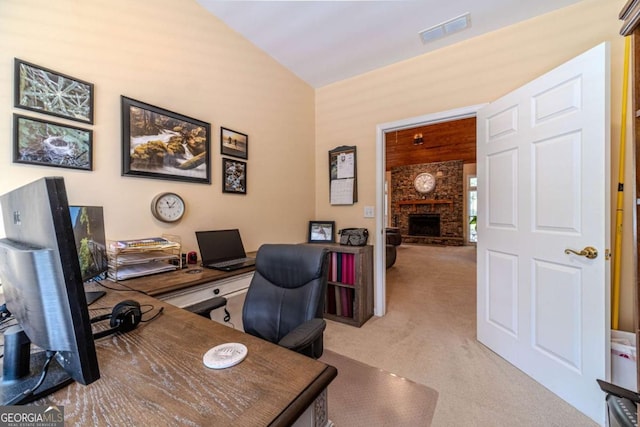 carpeted office space with a fireplace and vaulted ceiling