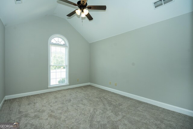 spare room featuring lofted ceiling, light colored carpet, and ceiling fan