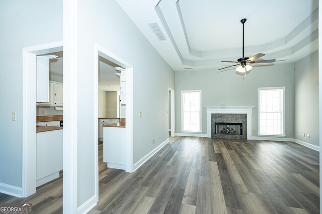 unfurnished living room with ceiling fan, dark hardwood / wood-style flooring, and a raised ceiling