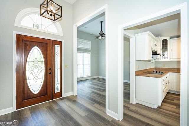 foyer entrance with dark hardwood / wood-style flooring and ceiling fan with notable chandelier