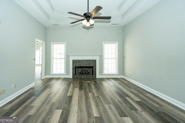 unfurnished living room with a raised ceiling, plenty of natural light, dark hardwood / wood-style floors, and a fireplace