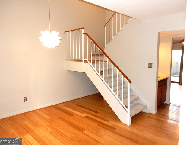 staircase with hardwood / wood-style flooring and an inviting chandelier