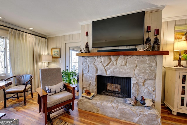 living area with hardwood / wood-style flooring, ornamental molding, and a fireplace