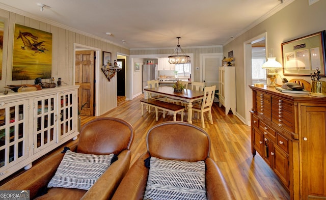 dining room with ornamental molding, light hardwood / wood-style floors, and a notable chandelier