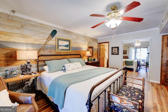 bedroom with hardwood / wood-style flooring, ornamental molding, ceiling fan, and wood walls