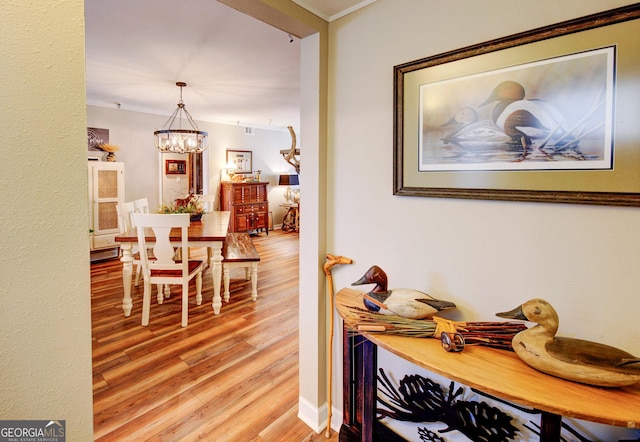 interior space with an inviting chandelier, ornamental molding, and hardwood / wood-style floors