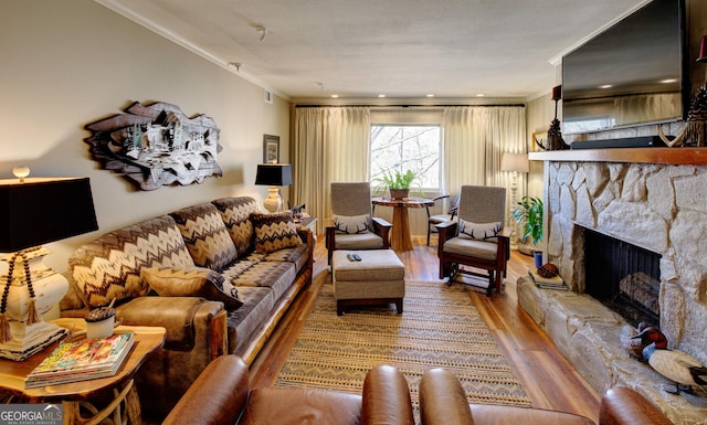 living room with ornamental molding, wood-type flooring, and a stone fireplace