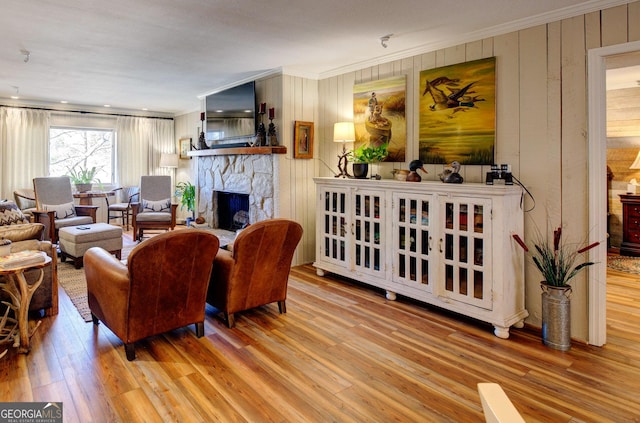 living room featuring crown molding, a stone fireplace, and light hardwood / wood-style floors