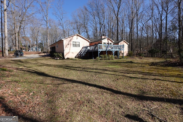 view of side of property featuring a yard, a chimney, and a wooden deck