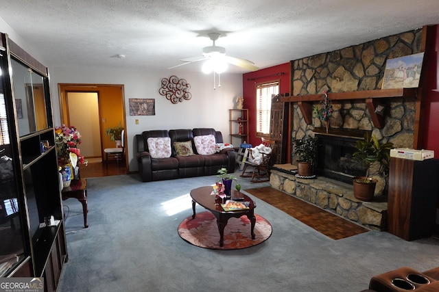 living area featuring a textured ceiling, carpet floors, a fireplace, and a ceiling fan