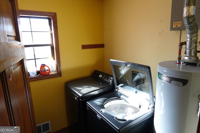 clothes washing area featuring laundry area, water heater, visible vents, and washing machine and clothes dryer