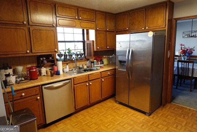 kitchen with stainless steel appliances, light countertops, brown cabinets, and a sink