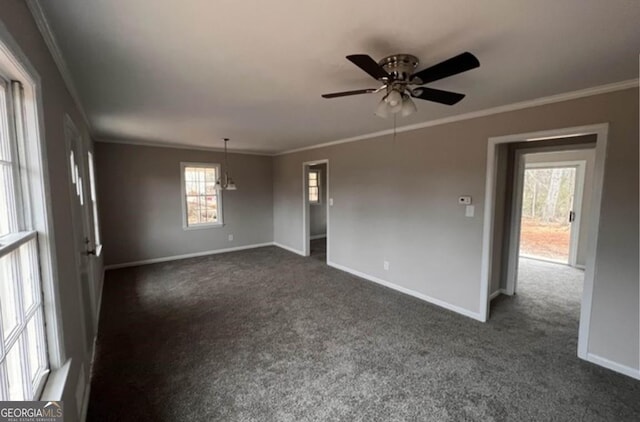 empty room featuring dark colored carpet, ceiling fan, and crown molding