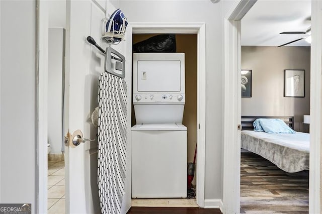 clothes washing area with ceiling fan, tile patterned floors, and stacked washing maching and dryer