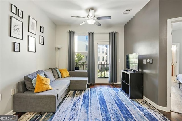 living room featuring ceiling fan and dark hardwood / wood-style floors