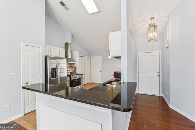 kitchen with pendant lighting, kitchen peninsula, stainless steel fridge with ice dispenser, and white cabinets