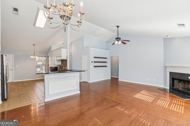 kitchen with tasteful backsplash, decorative light fixtures, stainless steel fridge, kitchen peninsula, and white cabinets