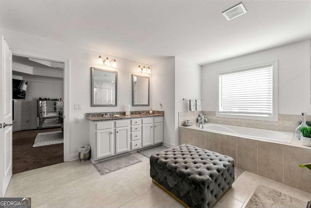 bathroom featuring vanity, tiled bath, and tile patterned floors