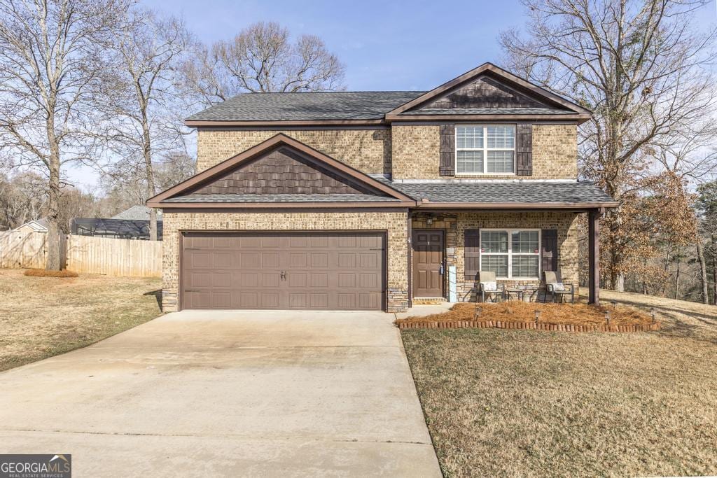 view of front of home featuring a garage, a front yard, and covered porch