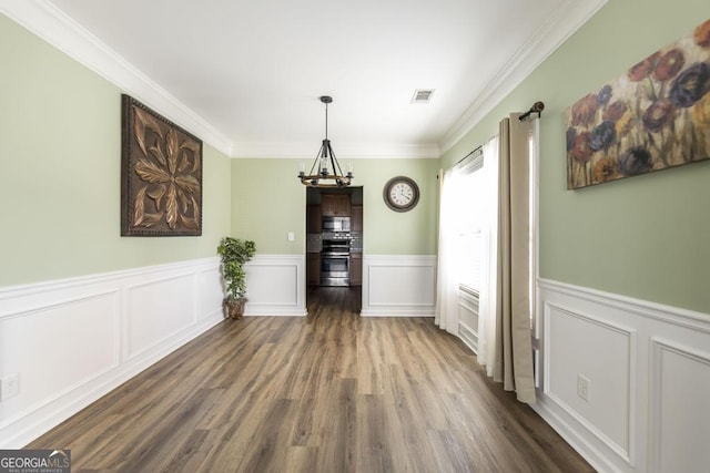 unfurnished dining area featuring dark hardwood / wood-style flooring, ornamental molding, and a chandelier