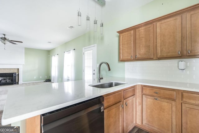 kitchen featuring sink, ceiling fan, black dishwasher, a fireplace, and kitchen peninsula