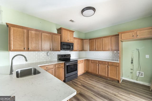 kitchen featuring sink, stainless steel range with electric cooktop, dark hardwood / wood-style flooring, light stone countertops, and decorative backsplash