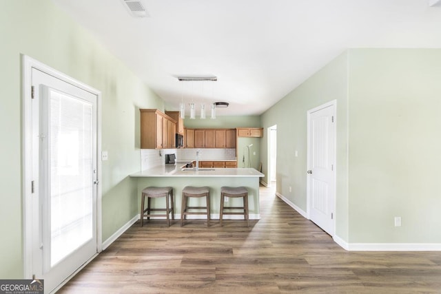 kitchen featuring wood-type flooring, track lighting, decorative backsplash, decorative light fixtures, and kitchen peninsula