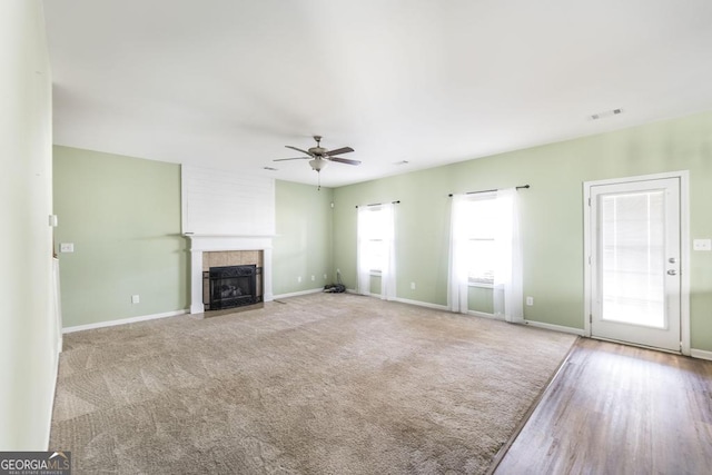 unfurnished living room featuring ceiling fan, light colored carpet, and a tile fireplace