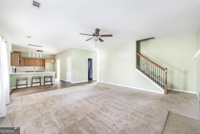 unfurnished living room with sink, carpet floors, and ceiling fan