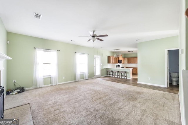 unfurnished living room with light colored carpet and ceiling fan