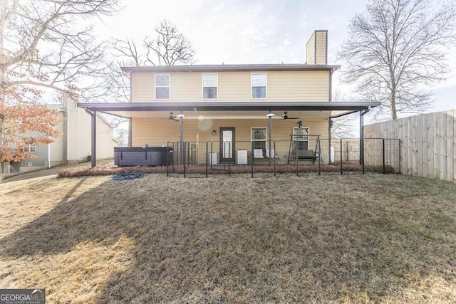 back of house featuring a yard and a hot tub