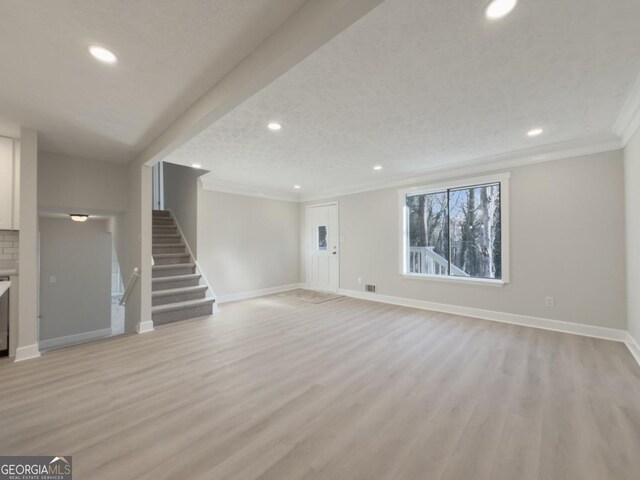 unfurnished living room featuring hardwood / wood-style flooring, crown molding, and a textured ceiling