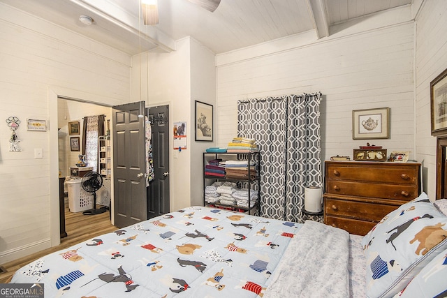 bedroom with ceiling fan, wood-type flooring, and beamed ceiling