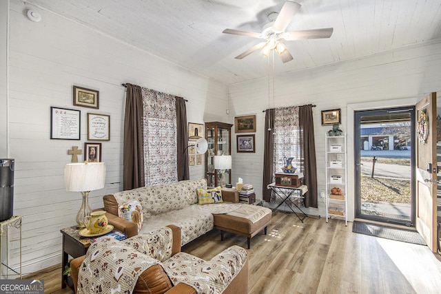 living room featuring wood walls, ceiling fan, and light hardwood / wood-style flooring