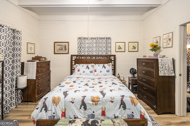 bedroom featuring beam ceiling and light hardwood / wood-style floors