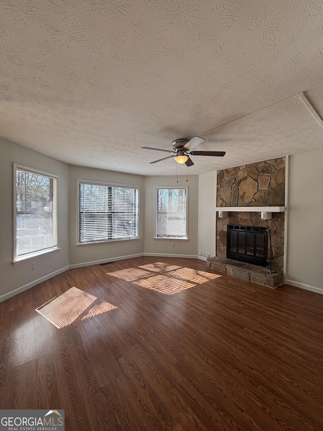 unfurnished living room with ceiling fan, wood-type flooring, a fireplace, and plenty of natural light