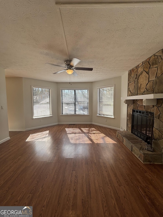 unfurnished living room featuring ceiling fan, a textured ceiling, a fireplace, and wood-type flooring