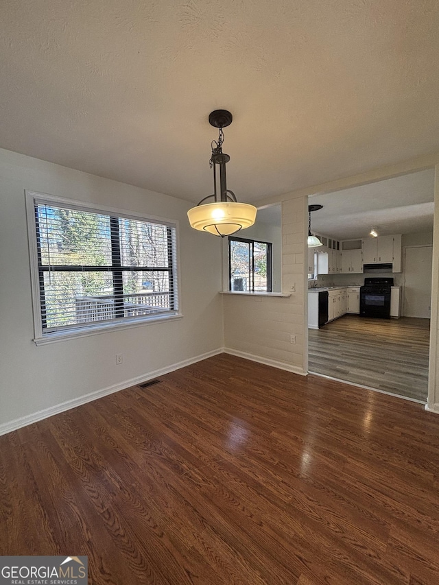 unfurnished dining area featuring dark hardwood / wood-style floors and a textured ceiling